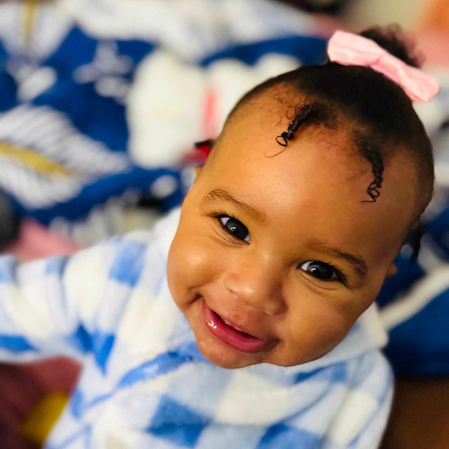 Jey-ïqa is registered to the contest to win money with this photo: baby, blue_and_white, checkered_clothing, child, closeup, cozy, curly_hair, cute, face, happy, head, indoor, infant, person, pink_bow, portrait, smiling, soft_focus, warm, young_child