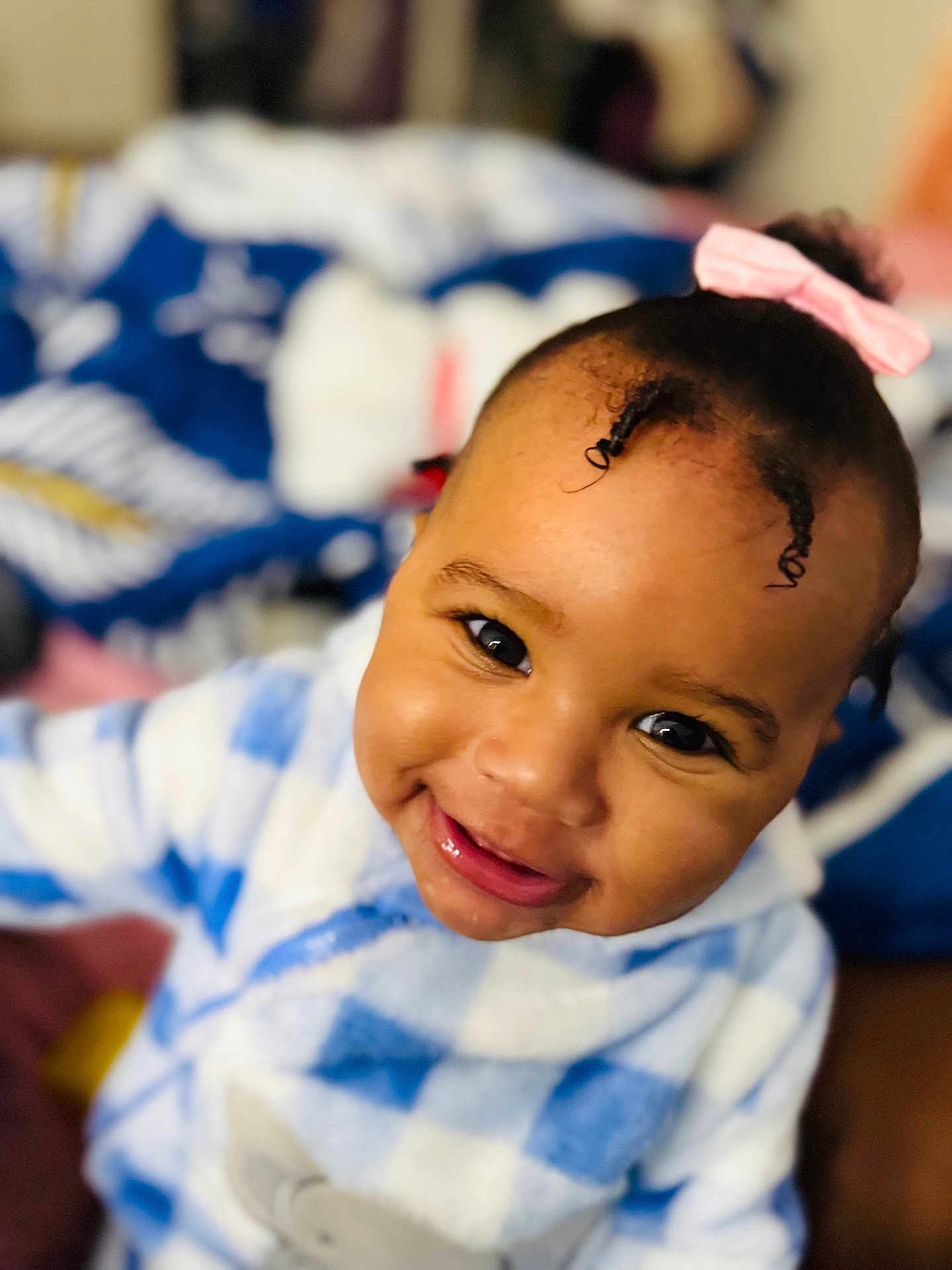 Jey-ïqa is registered to the contest to win money with this photo: baby, child, smiling, face, pink_bow, curly_hair, blue_and_white, checkered_clothing, cute, portrait, indoor, person, happy, cozy, closeup, head, infant, young_child, soft_focus, warm
