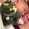 Jaxon is registered to the contest to win money with this photo: newborn, baby, sleeping, infant, person, blanket, hospital, wristband, camo_clothing, closeup, skin, hand, face, ear, soft_light, comfort, rest, parent, indoor, tenderness