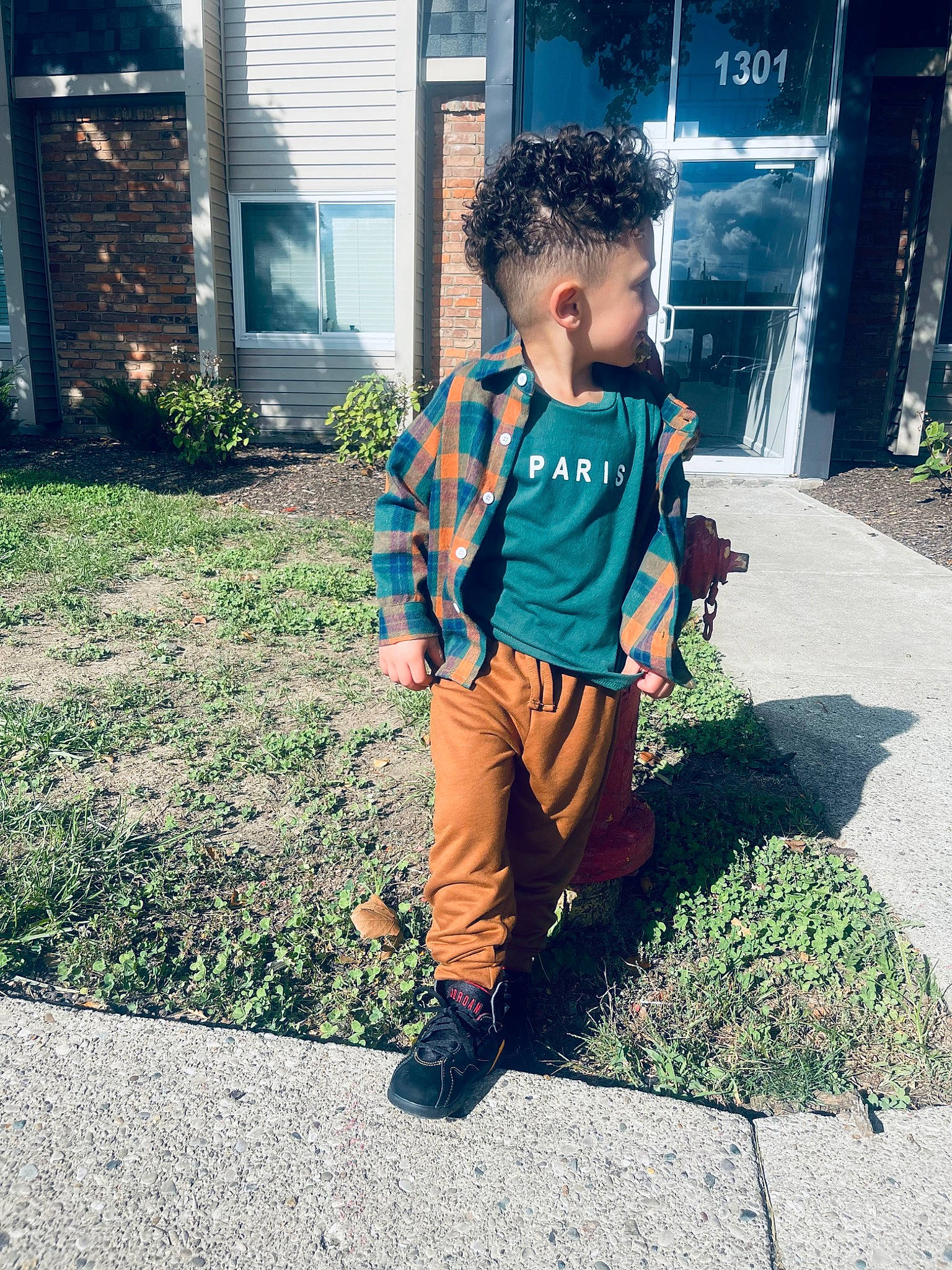 Jakhi is registered to the contest to win money with this photo: asphalt, denim, electric_blue, eyewear, fun, grass, happy, house, leisure, pattern, person, plant, sidewalk, sitting, sleeve, sportswear, standing, t_shirt, tints_and_shades, toddler