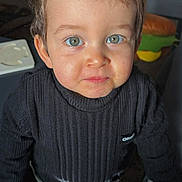 Louis a rejoint le concours — aidez-le/la à gagner de superbes lots ! background, blue_eyes, child, clothing, cozy, curious, cute, expression, face, furniture, hair, home, indoor, person, smile, standing, sweater, toddler, toy, young