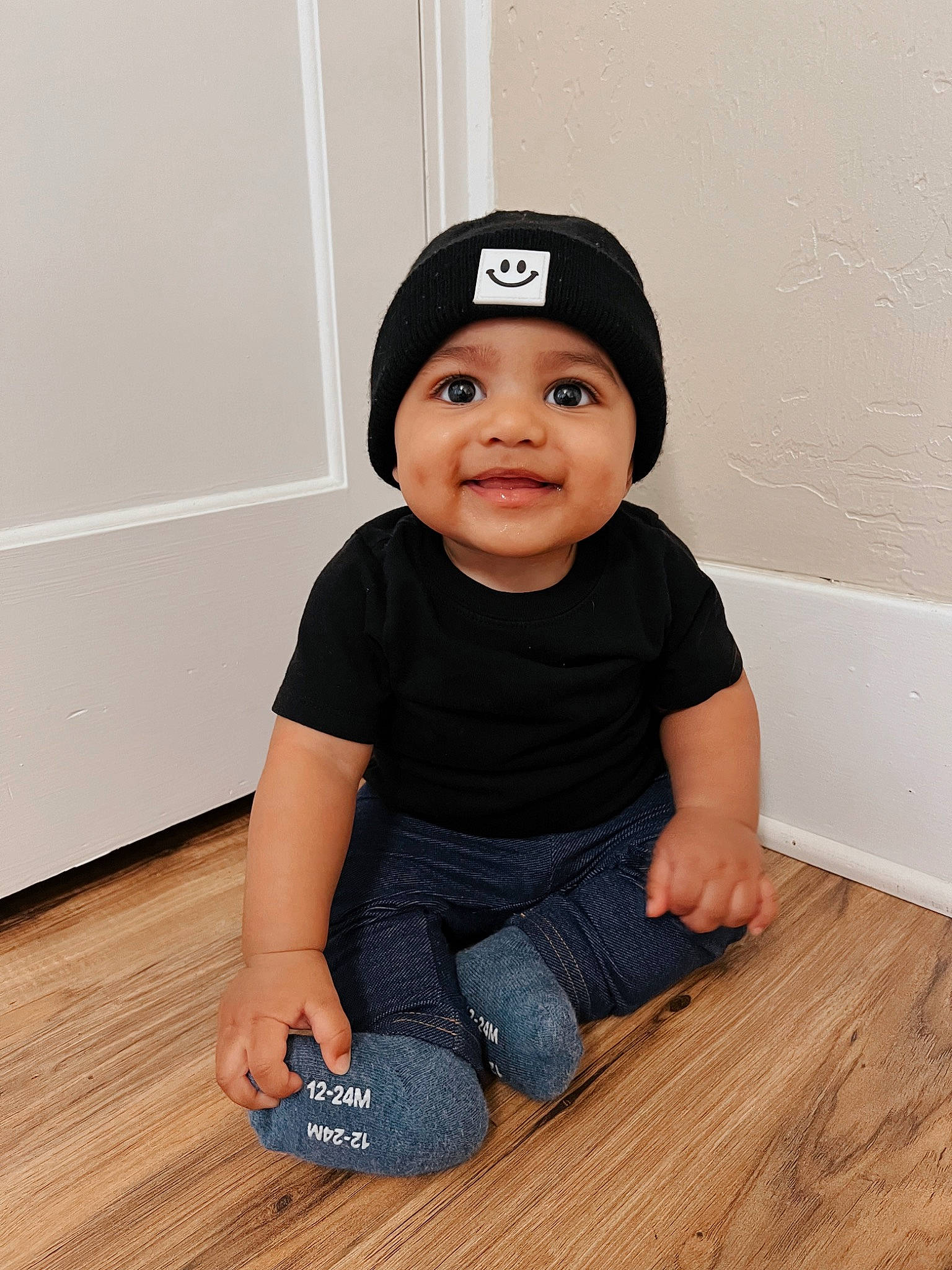 David Jaymes is registered to the contest to win money with this photo: baby_toddler_clothing, cap, cheek, clothing, flooring, foot, hardwood, headwear, human_leg, joy, knee, laminate_flooring, person, sitting, sleeve, smile, t_shirt, thigh, toddler, varnish