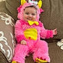 baby, child, costume, pink, yellow, monster, plush, furry, smile, couch, indoor, cute, face, infant, seated, clothing, playful, soft, happy, home