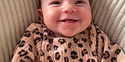 Léana participe au concours pour gagner de l'argent avec cette photo : baby, infant, smiling, leopard_print, clothing, cushion, texture, happy, child, portrait, indoor, comfort, cute, person, face, young_child, seated, cozy, apparel, expression
