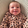 baby, infant, smiling, leopard_print, clothing, cushion, texture, happy, child, portrait, indoor, comfort, cute, person, face, young_child, seated, cozy, apparel, expression