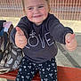 child, smiling, thumbs_up, sitting, bench, outdoor, sunlight, sweatshirt, love_text, floral_leggings, bag, brick_wall, window, reflection, happy, person, casual_clothing, young_child, cute, fashion