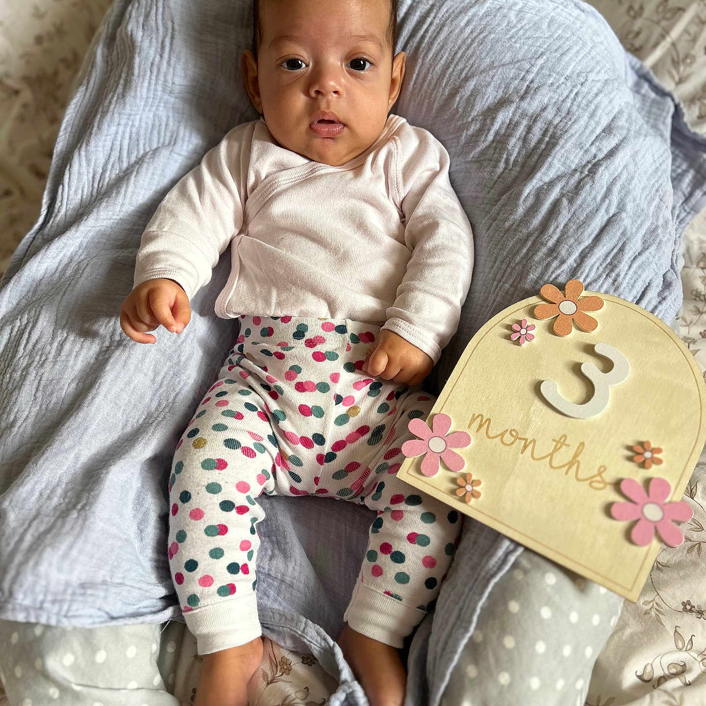 Mareva participe au concours pour gagner de l'argent avec cette photo : 3_months, baby, baby_clothing, blanket, cute, decor, face, feet, flower, gray, hand, indoor, infant, lounger, lying_down, milestone_sign, pink, polka_dot, portrait, wooden_sign