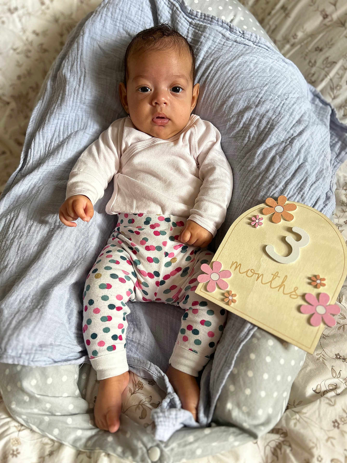 Mareva participe au concours pour gagner de l'argent avec cette photo : baby, infant, 3_months, milestone_sign, polka_dot, baby_clothing, pink, gray, blanket, lounger, face, feet, hand, lying_down, cute, decor, wooden_sign, flower, indoor, portrait