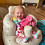 baby, infant, smiling, colorful_clothing, stuffed_animal, pink_bunny, inflatable_chair, wooden_floor, blanket, owl_pattern, happy, indoor, child, cute, plush_toy, sitting, face, head, person, footwear