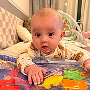 Victoria joined the competition — help win amazing prizes! baby, infant, onesie, bear_pattern, play_mat, colorful, fish_shapes, hand, curious, wide_eyes, indoor, couch, blanket, soft_toys, child, cute, exploring, tummy_time, face, expression