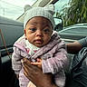 baby, child, infant, hat, knit_hat, pink_jacket, cute, person, hand, car_interior, car_window, trees, cloudy_sky, portrait, warm_clothing, cozy, cute_baby, holding, looking_at_camera, seated