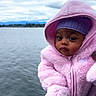 baby, child, pink_hoodie, purple_hat, water, lake, cloudy_sky, outdoor, person, hand, portrait, warm_clothing, cute, young_child, winter_wear, nature, calm, expression, holding, scenery