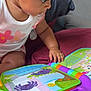 toddler, child, toy, book, colorful, hand, face, indoor, cushion, clothing, curious, reading, purple, pink, white, play, baby, expression, seat, learning
