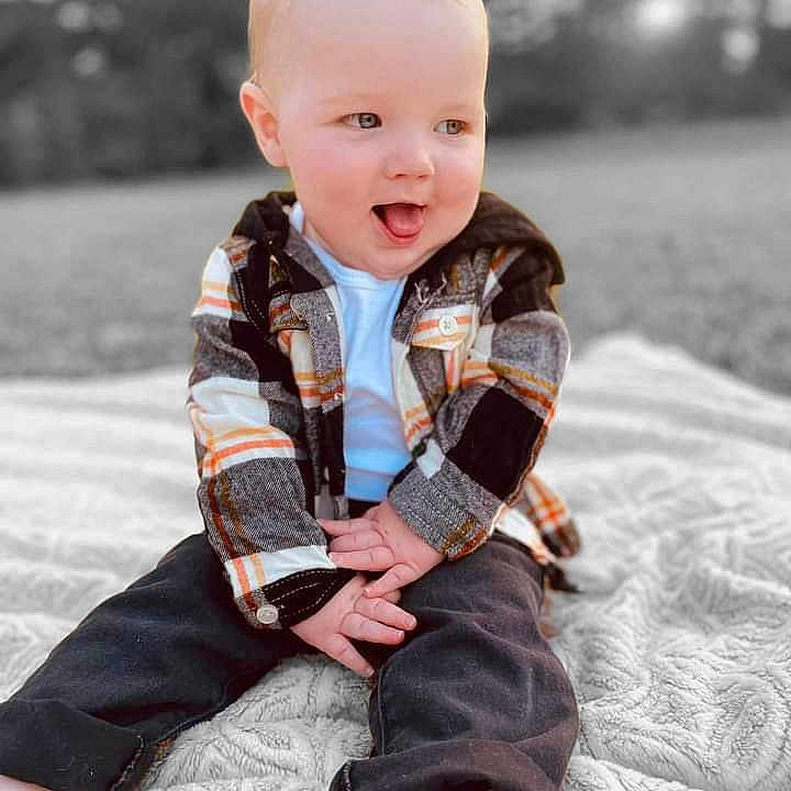 Kohen James is registered to the contest to win money with this photo: baby, babylaughing, blazer, blonde, clothing, coat, face, hair, happy, head, jacket, jeans, laughing, pants, person, photography, portrait, scarf, sitting, smile
