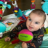 Gabin participe au concours pour gagner de l'argent avec cette photo : baby, infant, play_mat, toy_ball, colorful, smiling, happy, child, indoor, play_toys, bird_toy, bee_toy, dinosaur_print, clothing, face, hands, floor, bright_colors, cute, tummy_time