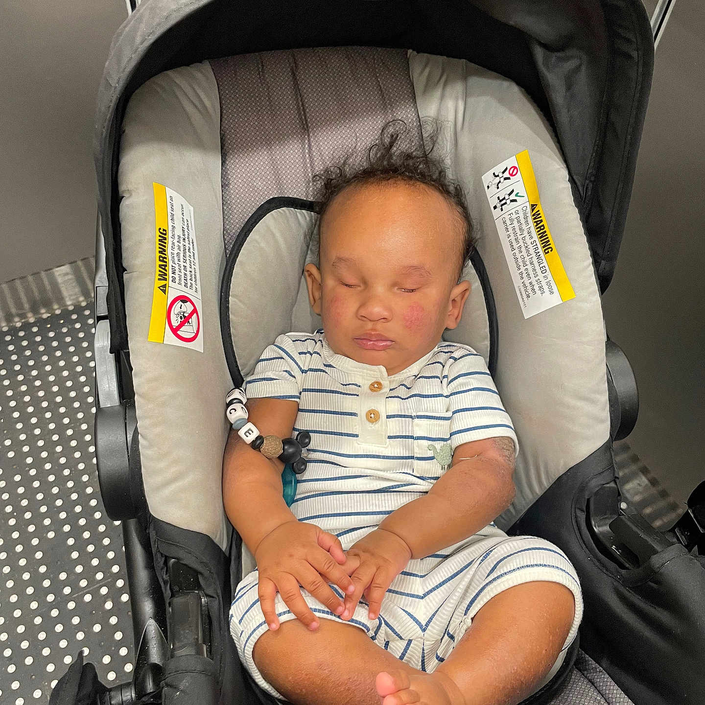 Truce Clarke is registered to the contest to win money with this photo: baby, car_seat, child, curly_hair, cushion, elevator, feet, hands, indoor, infant, metal, modern, peaceful, person, relaxed, seat, sleeping, striped_clothing, transportation, warning_label