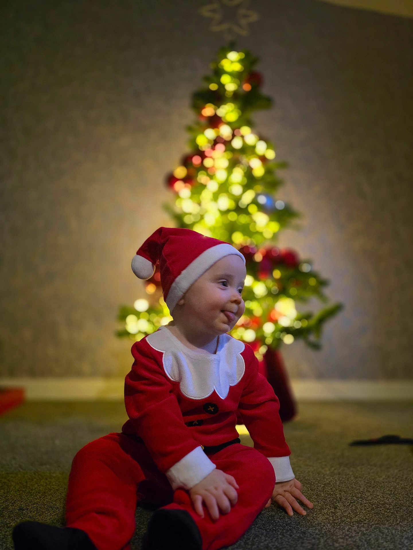 Cillian joined the competition — help win amazing prizes! child, toddler, santa_claus_costume, christmas_tree, holiday, festive, indoor, carpet, blurred_background, lights, decoration, red_clothing, hat, playful, smiling, cute, celebration, holiday_season, portrait, happy