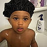 Aaron joined the competition — help win amazing prizes! toddler, child, bathroom, shower_cap, wet_skin, soap, shampoo, bottle, face, eyes, expression, person, skin, water_droplets, bath, young_child, headwear, curious, indoor, portrait