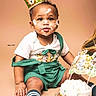 baby, birthday, cake, crown, face_paint, green_clothing, suspenders, smiling, sitting, celebration, first_birthday, sprinkles, animal_toppers, cute, happy, indoor, child, one_year_old, party, photography