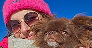 Lady a rejoint le concours — aidez-le/la à gagner de superbes lots ! beanie, blue_sky, brown_dog, closeup, cuddle, dog, fluffy, happy, jacket, long_hair, outdoor, person, pet, pink_hat, portrait, scarf, selfie, sunglasses, sunlight, winter