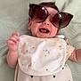 Lottie Mae joined the competition — help win amazing prizes! baby, child, sunglasses, smiling, bib, cute, infant, happy, face, portrait, clothing, lying_down, hand, pale_green, blanket, indoor, closeup, funny, adorable, heart_pattern