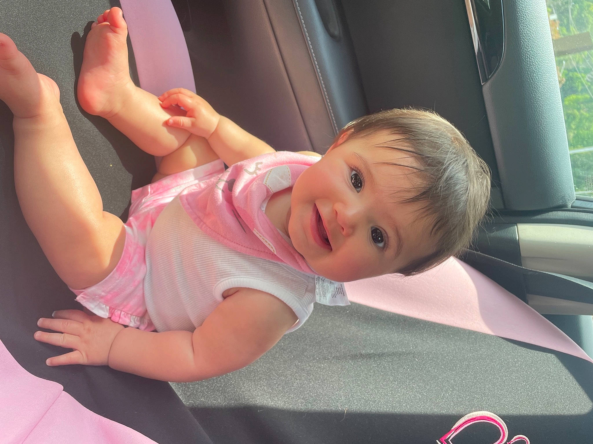 Raelyn is registered to the contest to win money with this photo: car, comfort, face, facial_expression, finger, gesture, hand, happy, human_body, joint, leg, motor_vehicle, muscle, person, pink, shoulder, skin, smile, toddler, vehicle