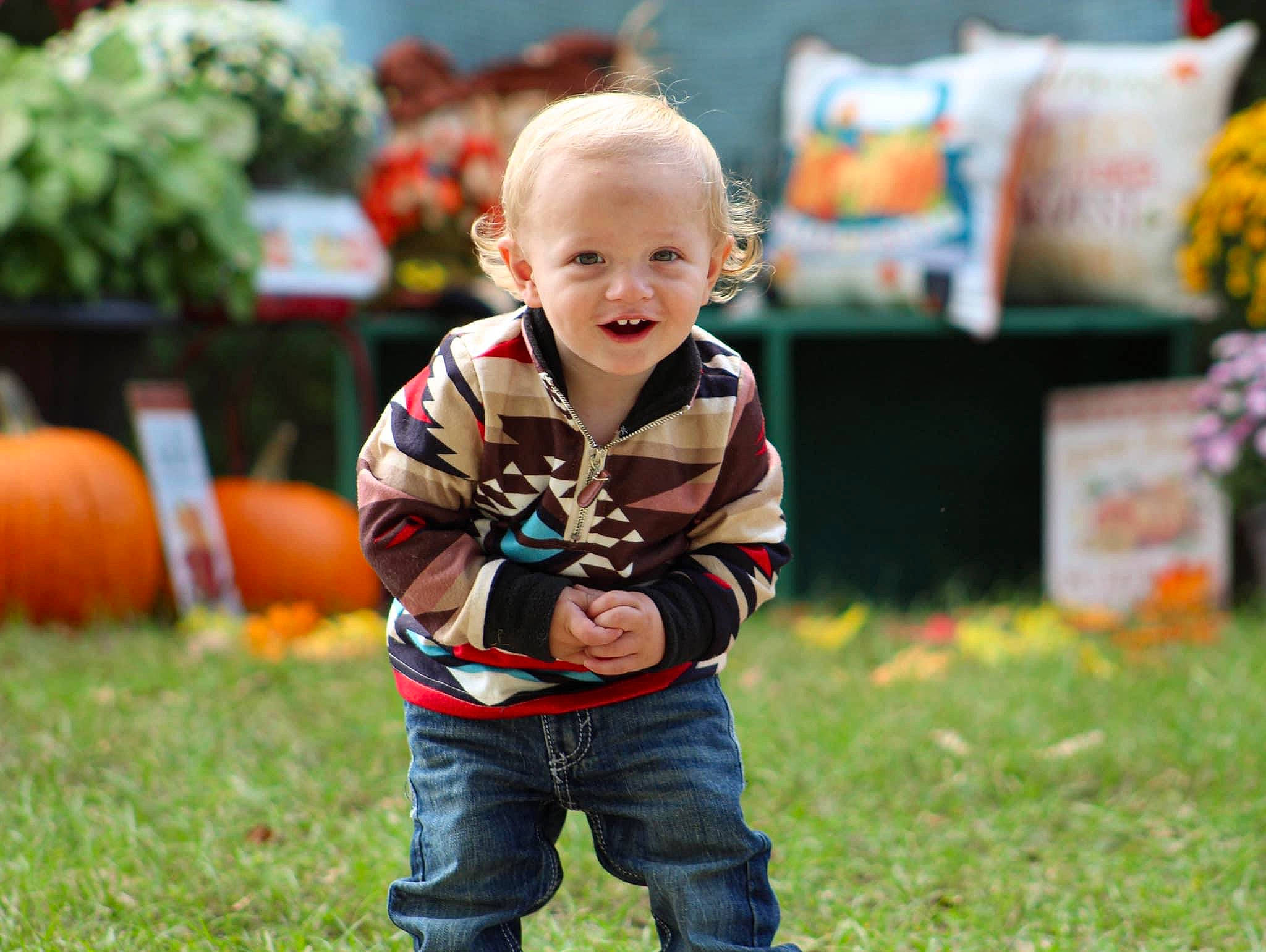 Ruger is registered to the contest to win money with this photo: baby, baby_toddler_clothing, calabaza, child, cucurbita, flooring, fun, gourd, grass, happy, lawn, leg, leisure, orange, people_in_nature, person, plant, recreation, sitting, smile