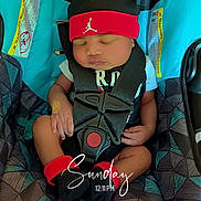 Brylon is registered to the contest to win money with this photo: baby, car_seat, headband, red, sleeping, child, infant, socks, black_clothing, safety_harness, patterned_fabric, indoors, peaceful, cute, resting, small_hands, wearing, comfort, seatbelt, nap
