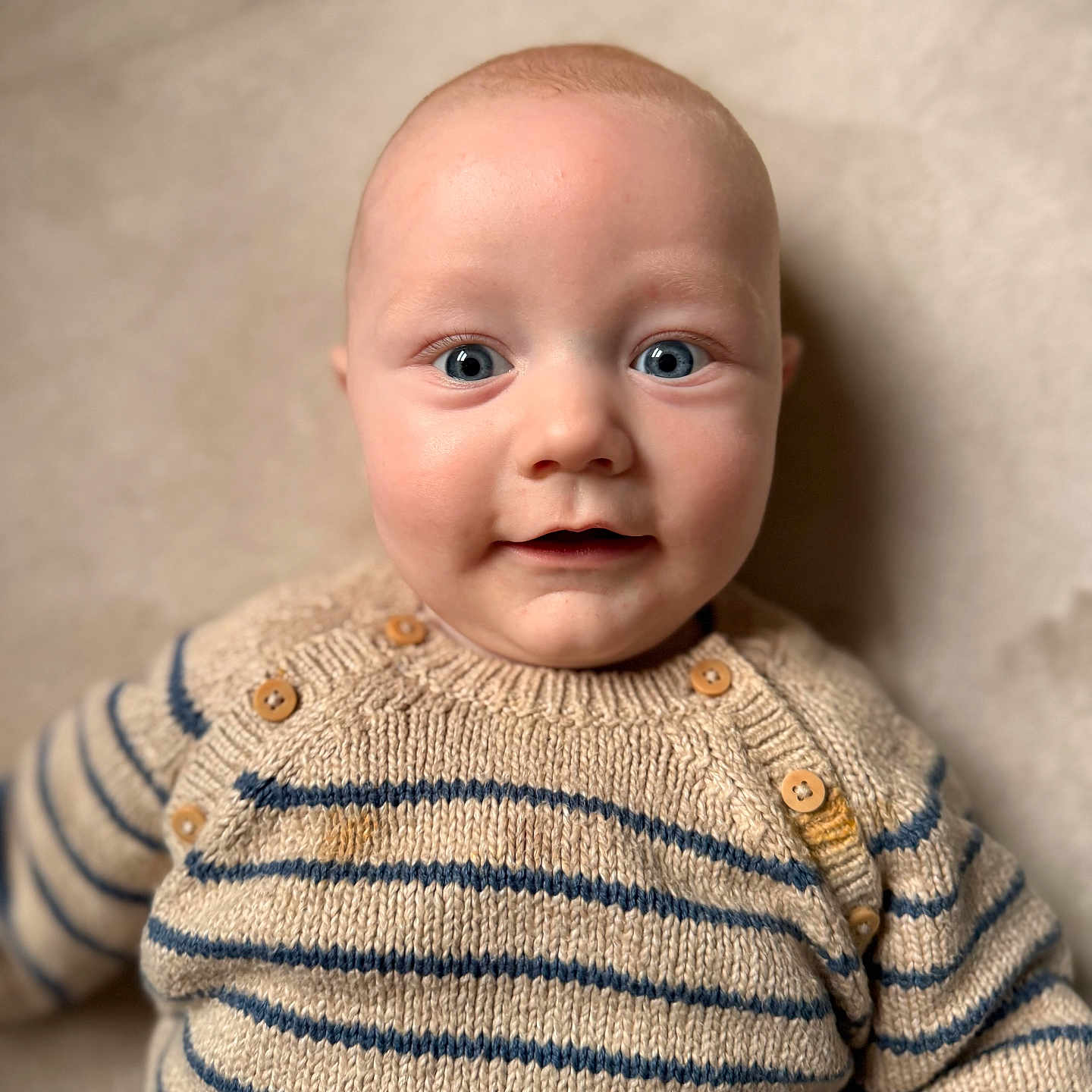 Antonn a rejoint le concours — aidez-le/la à gagner de superbes lots ! baby, baby_clothing, bald_head, blue_eyes, buttons, cheeks, child, close_up, cozy, fair_skin, indoors, infant, knitwear, looking_at_camera, portrait, reclining, smile, soft_background, striped_sweater, sweater