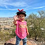 Celina is registered to the contest to win money with this photo: toddler, child, smiling, waving, hat, pink_shirt, jeans, pink_shoes, rock, outdoor, blue_sky, sunny, nature, desert_plants, portrait, happy, casual_clothing, daylight, fun, cute