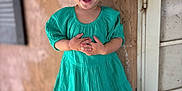 Celina is registered to the contest to win money with this photo: child, toddler, smiling, laughing, headband, dress, teal, standing, wall, texture, outdoor, happy, person, cute, portrait, fashion, feet, shoes, hands, young