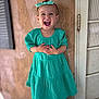 child, toddler, smiling, laughing, headband, dress, teal, standing, wall, texture, outdoor, happy, person, cute, portrait, fashion, feet, shoes, hands, young
