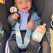 Wassim a rejoint le concours — aidez-le/la à gagner de superbes lots ! baby, bottle, car_seat, child, clothing, cute, daylight, face, happy, infant, jacket, outside, pants, person, safety, seatbelt, sitting, smiling, socks, young