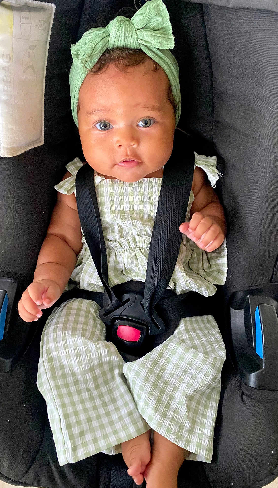 Sia participe au concours pour gagner de l'argent avec cette photo : baby, child, car_seat, green_bow, green_outfit, straps, sitting, cute, portrait, infant, face, headband, clothing, hands, feet, indoor, secure, looking_at_camera, expression, closeup