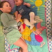 Colton is registered to the contest to win money with this photo: child, baby, siblings, blanket, winnie_the_pooh, cast, clothing, smiling, laying_down, indoor, cute, face, person, young, brother, toddler, happy, colorful, bedroom, comfort