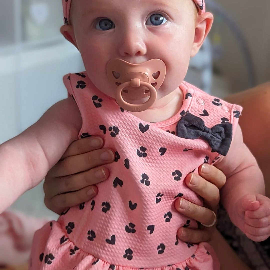 Ella is registered to the contest to win money with this photo: accessories, baby, biting, bodypart, clothing, face, finger, hand, happy, head, headband, person, photography, portrait, sitting, sleeve, yawning