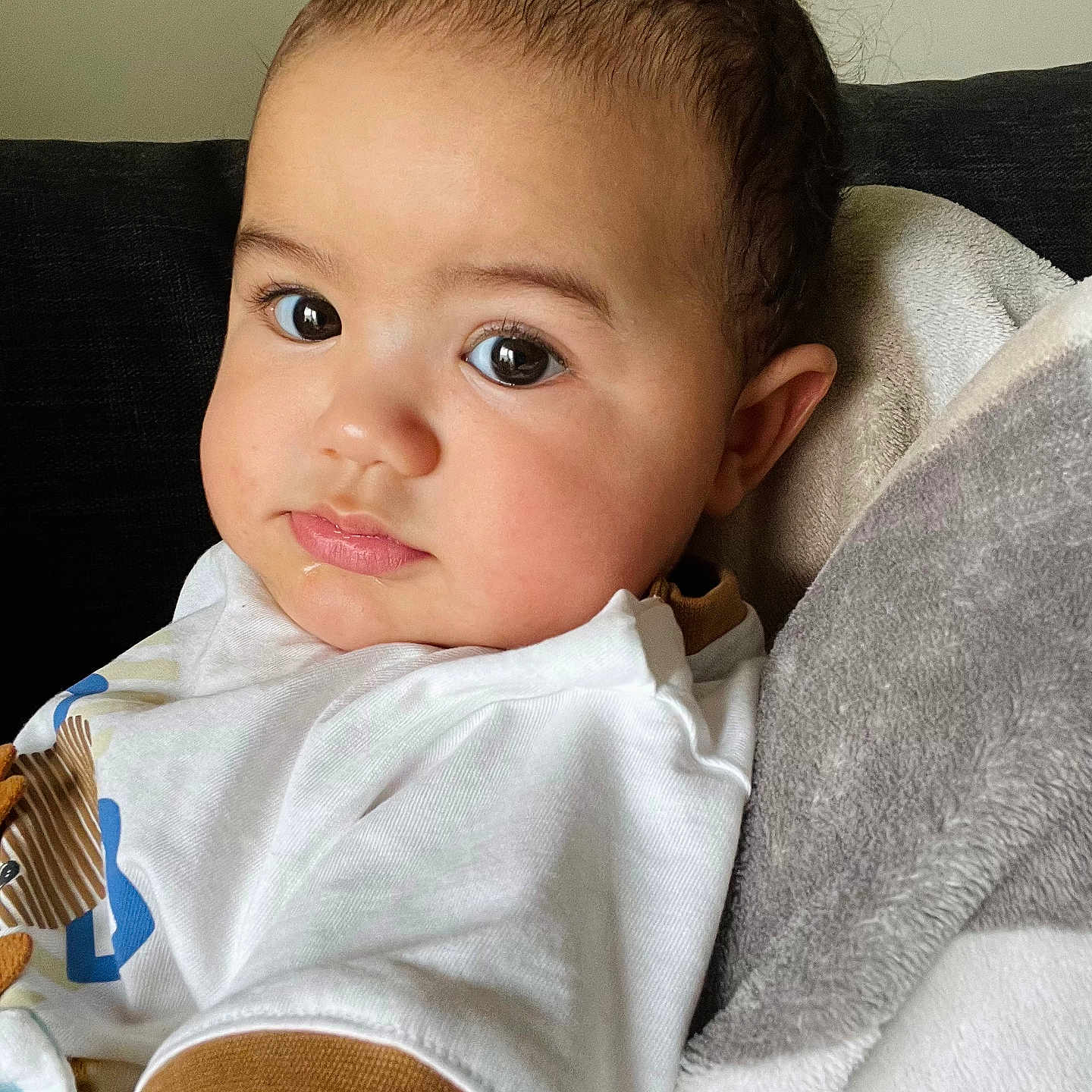 Jomani participe au concours pour gagner de l'argent avec cette photo : baby, blanket, brownhair, clothing, couch, cushion, face, furniture, hair, happy, head, homedecor, newborn, person, photography, portrait, sitting, sleeve, smile, t_shirt