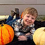 child, boy, smiling, pumpkin, orange_pumpkin, white_pumpkin, plaid_shirt, jeans, boots, blanket, outdoor, fall, autumn, grass, wall, happy, portrait, casual_clothing, cute, young