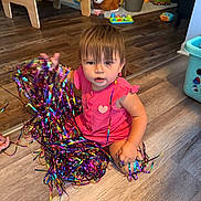 Nova is registered to the contest to win money with this photo: toddler, child, sitting, smiling, pink_outfit, party_streamers, colorful, toy_room, playroom, wooden_floor, plush_dog, toy_cars, baby_toys, indoor, portrait, young_child, festive, birthday, happy, playful