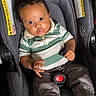 baby, child, car_seat, seat_belt, clothing, striped_shirt, polo_shirt, pants, socks, indoor, person, infant, seat, safety, curly_hair, black_hair, young_child, cute, wide_eyes, expression