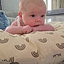 baby, infant, pillow, hand, face, skin, eyes, mouth, chewing, indoor, bedroom, blanket, pattern, striped, furniture, room, curtains, painting, person, lying_down