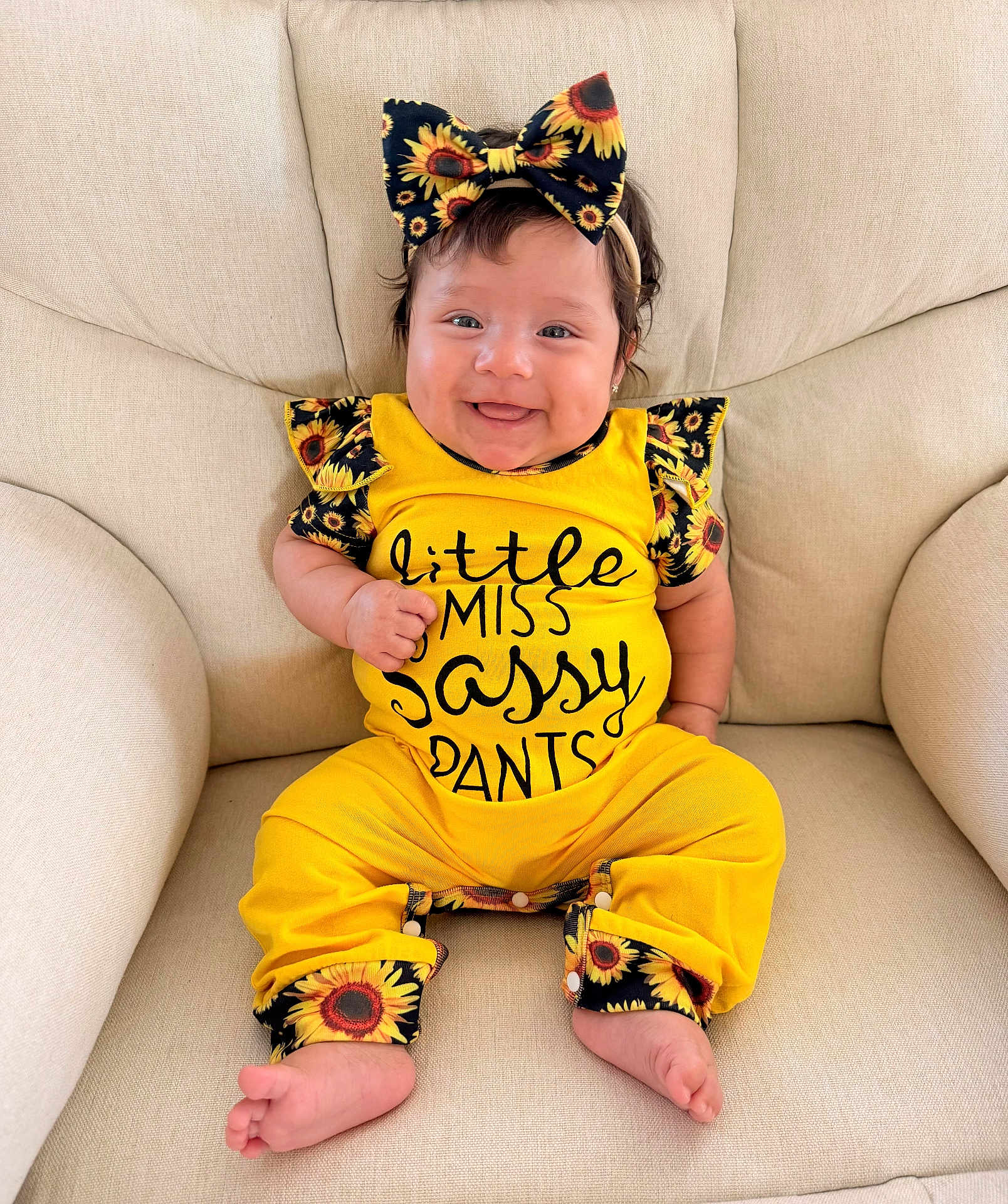 Isabella joined the competition — help win amazing prizes! baby, child, smiling, yellow_outfit, sunflower_pattern, bow, headband, sitting, indoor, armchair, happy, cute, portrait, clothing, feet, person, infant, comfortable, fashion, expression