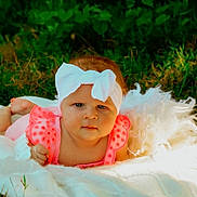 Oaklynn is registered to the contest to win money with this photo: baby, child, infant, outdoor, portrait, lying_down, blanket, white_blanket, pink_clothing, headband, bow, grass, garden, greenery, nature, red_hair, face, looking_at_camera, photography, cute