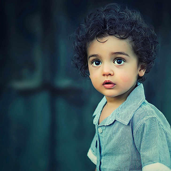 Lol joined the competition — help win amazing prizes! background_blur, blue_shirt, casual_clothing, child, closeup, curious, curly_hair, expression, face, head, indoors, innocence, looking_away, person, portrait, skin, standing, toddler, wide_eyes, young_child