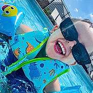 Zael is registered to the contest to win money with this photo: child, pool, water, floaties, sunglasses, happy, smiling, summer, outdoor, blue_sky, clouds, swimming, fun, sunny, splash, vacation, playful, life_jacket, dinosaur_pattern, inflatable