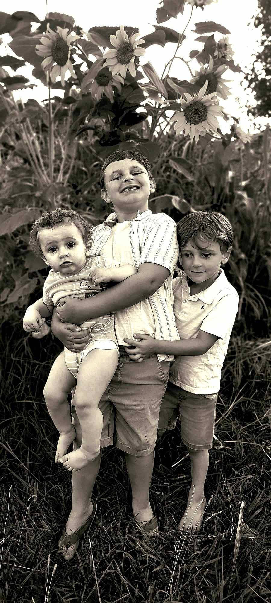 Mason is registered to the contest to win money with this photo: black, black_and_white, face, flash_photography, gesture, grass, happy, human_body, interaction, joy, leaf, monochrome, people_in_nature, person, photograph, plant, playing_with_kids, shorts, smile, style