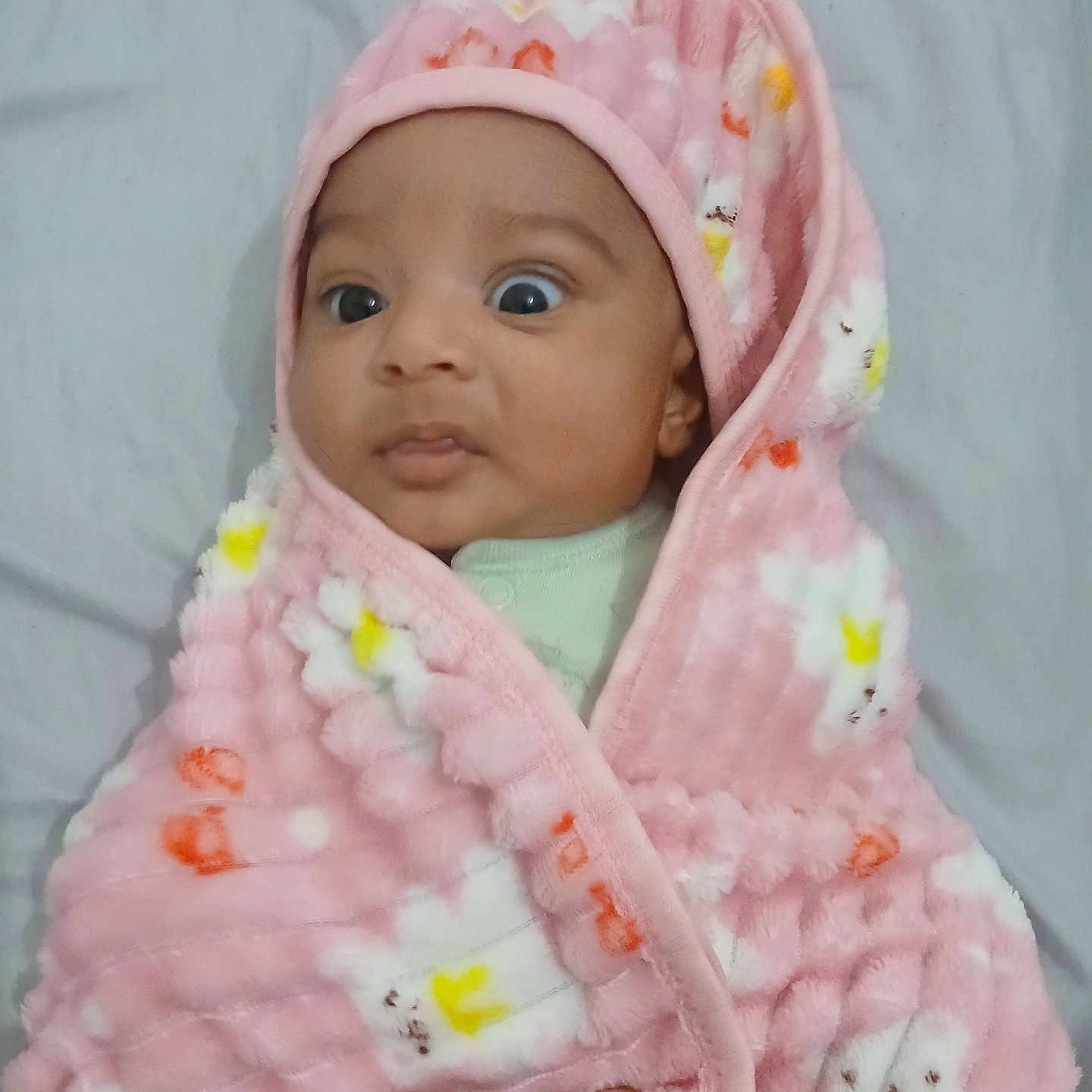 Enaya joined the competition — help win amazing prizes! baby, bed, blanket, child, cozy, cute, expression, flower_pattern, hand, indoors, infant, newborn, person, pink_blanket, portrait, sleepwear, soft_texture, warm, wide_eyes, wrapped