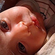 Erick Kalel is registered to the contest to win money with this photo: baby, infant, child, face, eyes, portrait, lying_down, blanket, clothing, cozy, indoor, close_up, curious, awake, skin, head, photograph, smartphone_screenshot, black_borders, home_screen