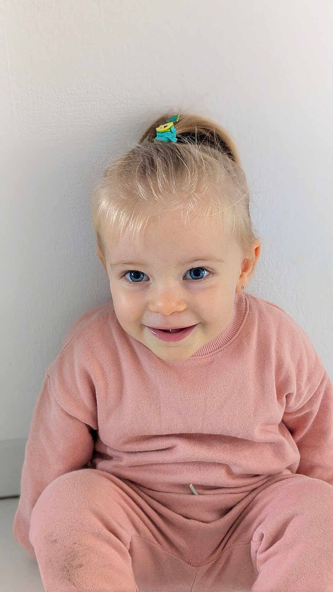 Lia a rejoint le concours — aidez-le/la à gagner de superbes lots ! toddler, child, smiling, blue_eyes, pink_clothing, hair_tie, pony_tail, sitting, indoor, white_wall, cute, happy, face, young_child, portrait, casual, cozy, innocence, person, clothing
