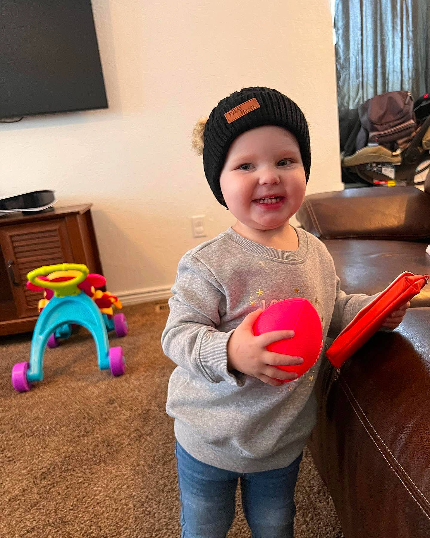 Adelynn is registered to the contest to win money with this photo: baby, baby_playing_with_toys, beauty, cap, child, curtain, fun, happy, hat, headwear, joy, leisure, person, play, product, room, sitting, sleeve, smile, t_shirt